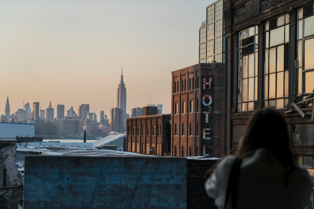 Una donna sulla terrazza di un edificio guarda la città sottostante, circondata da un'atmosfera di libertà e avventura.