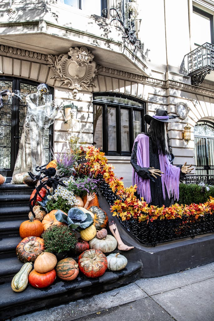 Halloween-themed decorations with pumpkins and witch on NYC brownstone steps.