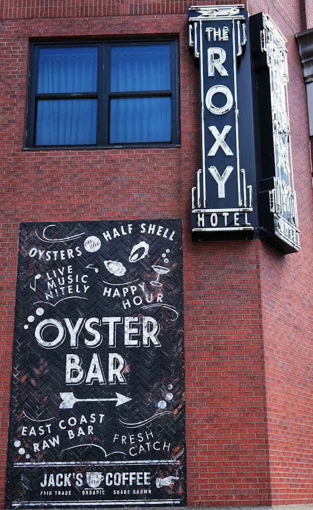 Vertical shot of Roxy Hotel and Oyster Bar sign on red brick in NYC.