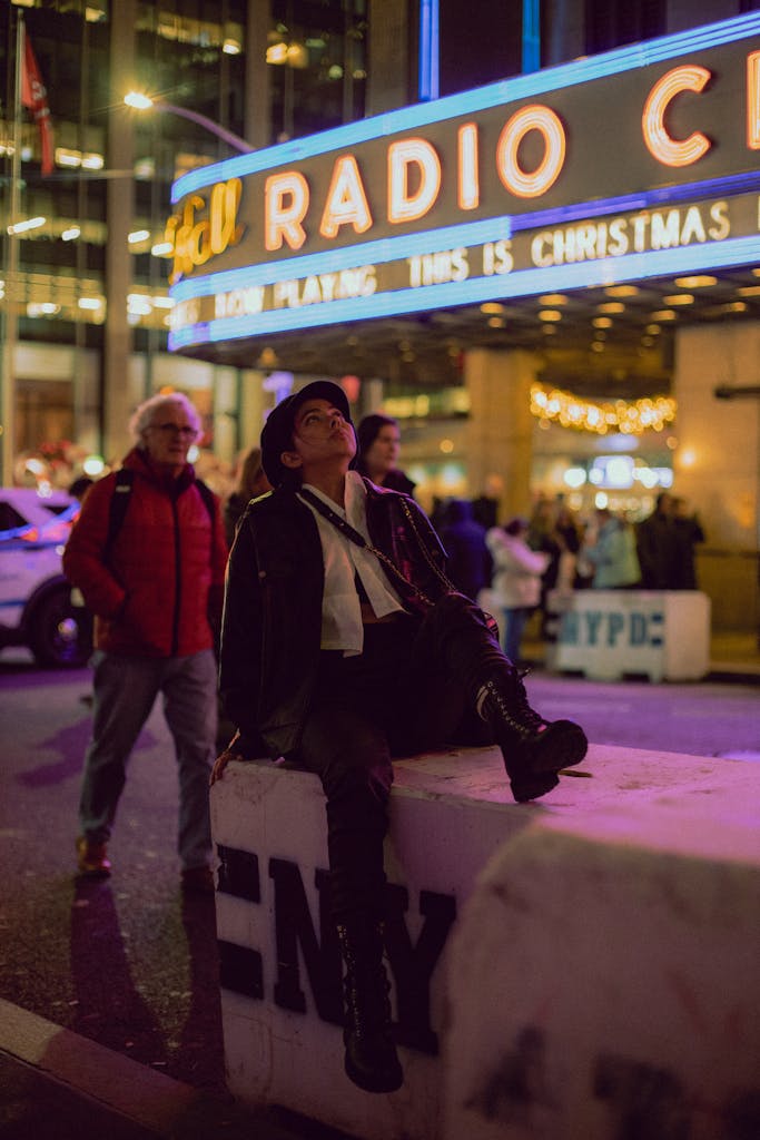 Fashionable woman sitting outside Radio City Music Hall in New York City at night.