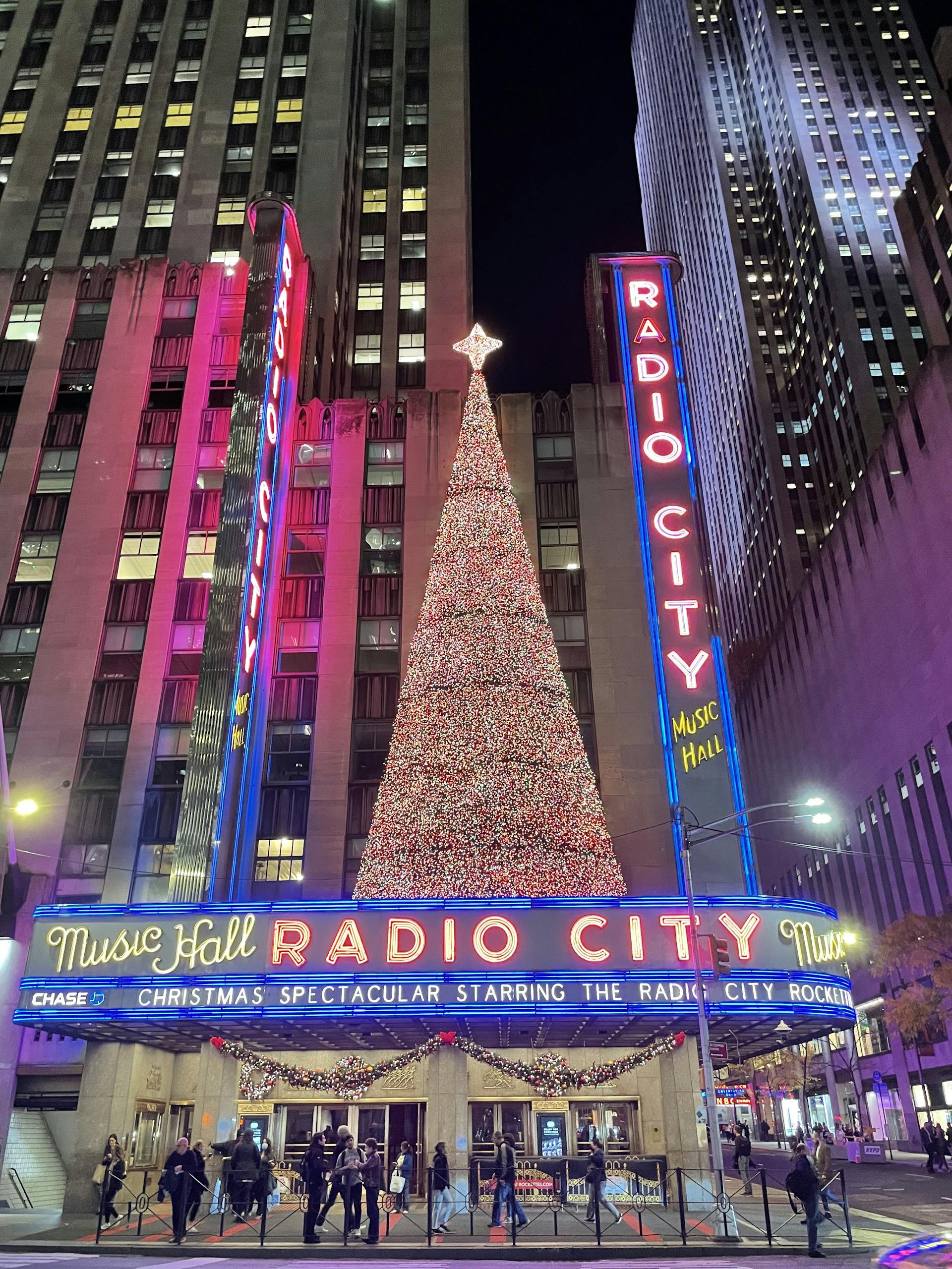 Festive Christmas tree and neon lights at Radio City Music Hall, New York City at night.