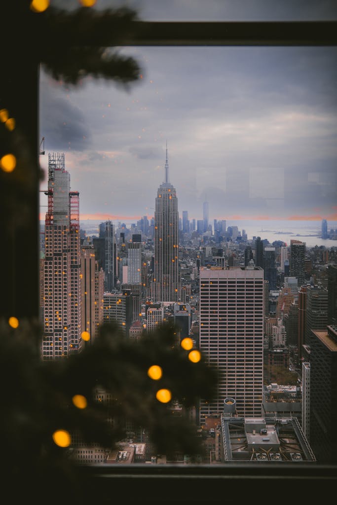 View of New York City skyline with Empire State Building through holiday decor. Perfect for travel and winter imagery.