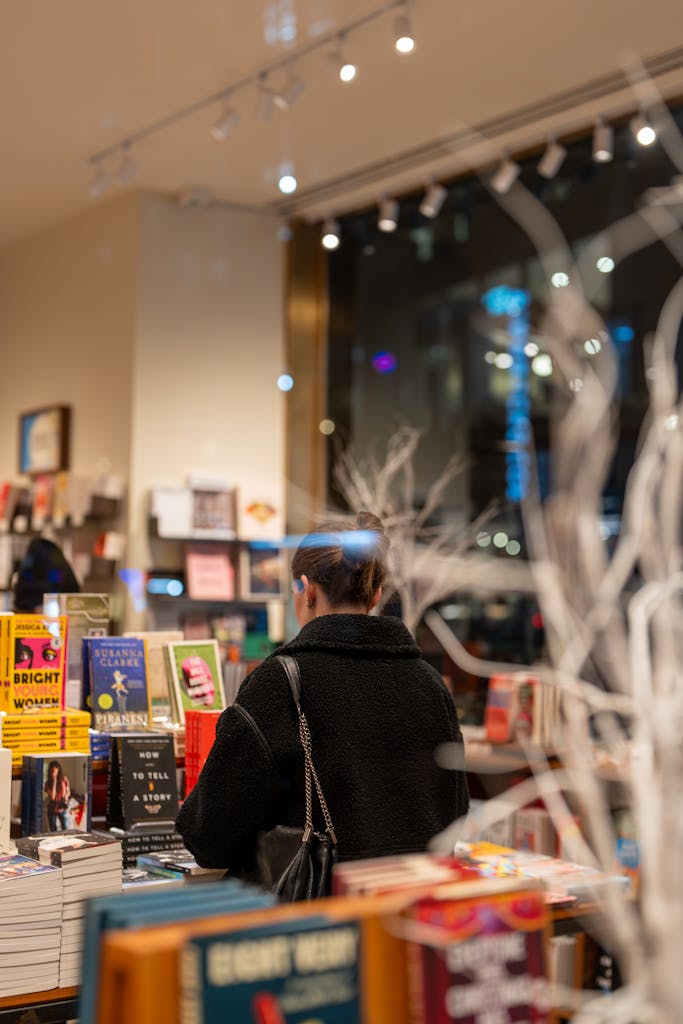 Person browsing books in a New York City bookstore at night.
